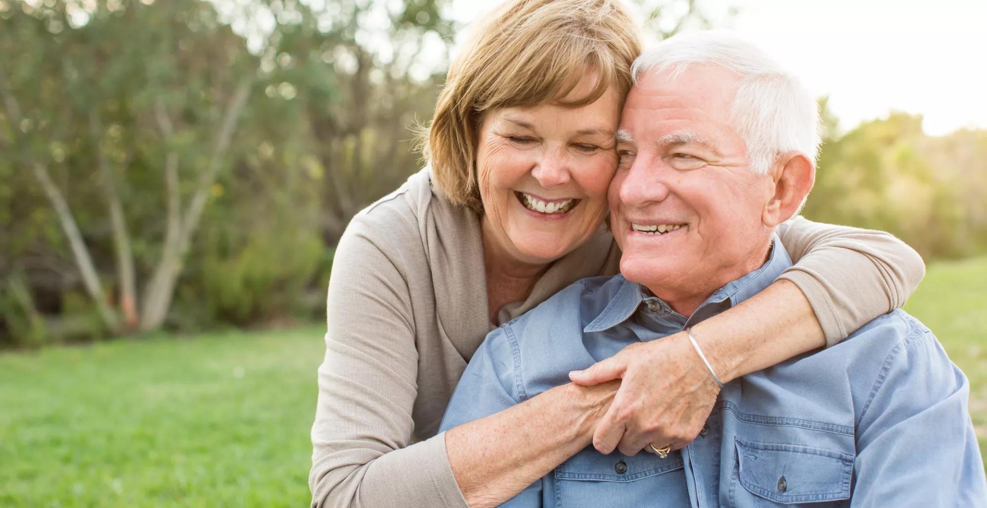 Senior female with glasses embracing a male senior, both are smiling