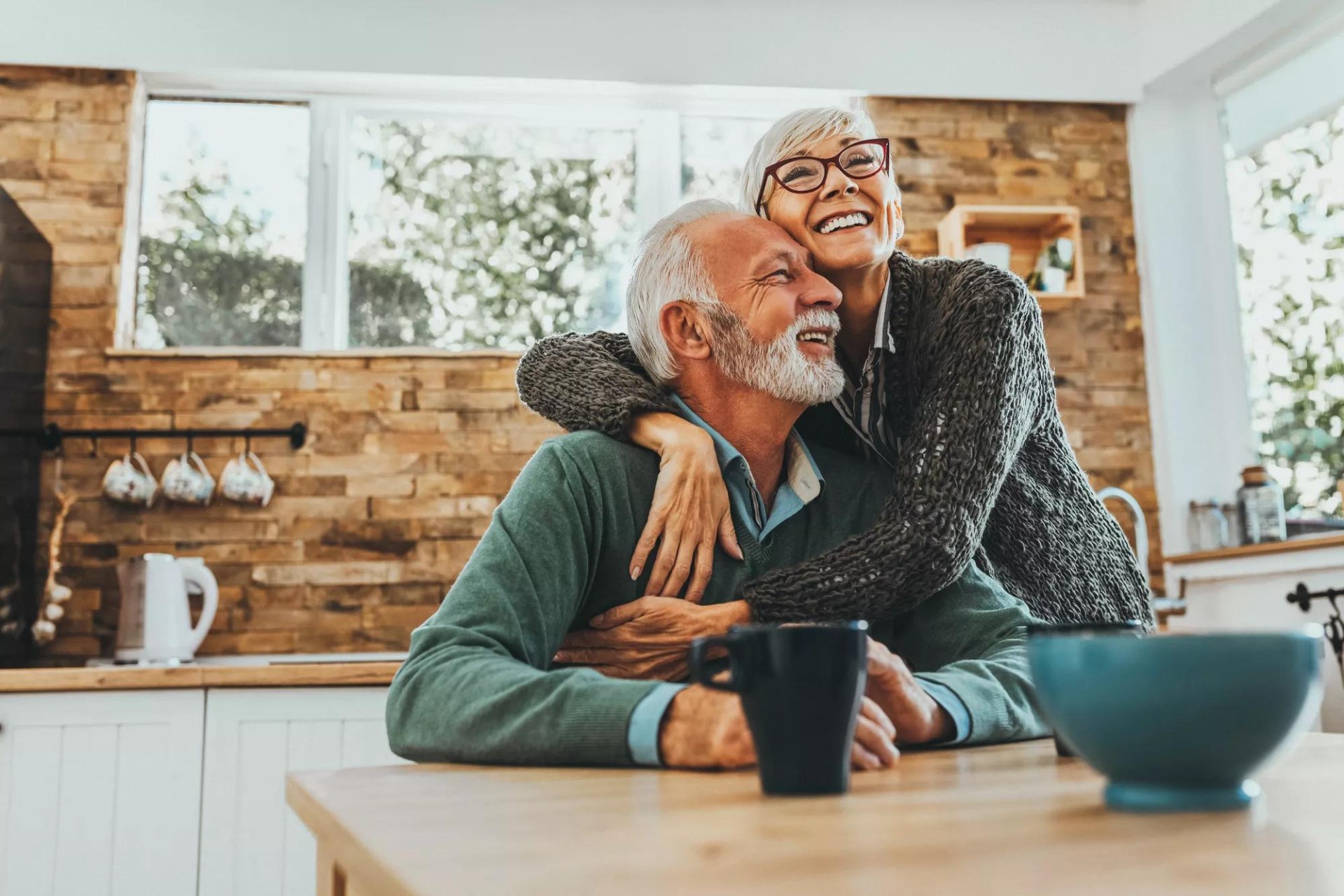Senior female with glasses embracing a male senior, both are smiling Senior female with glasses embracing a male senior, both are smiling